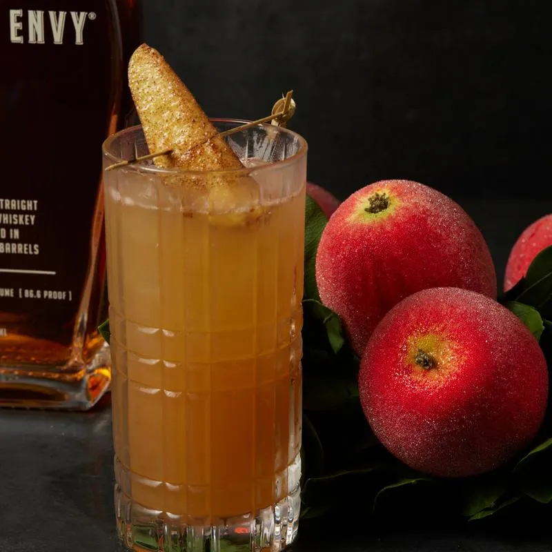 Forbidden Apple cocktail beside fresh apples.