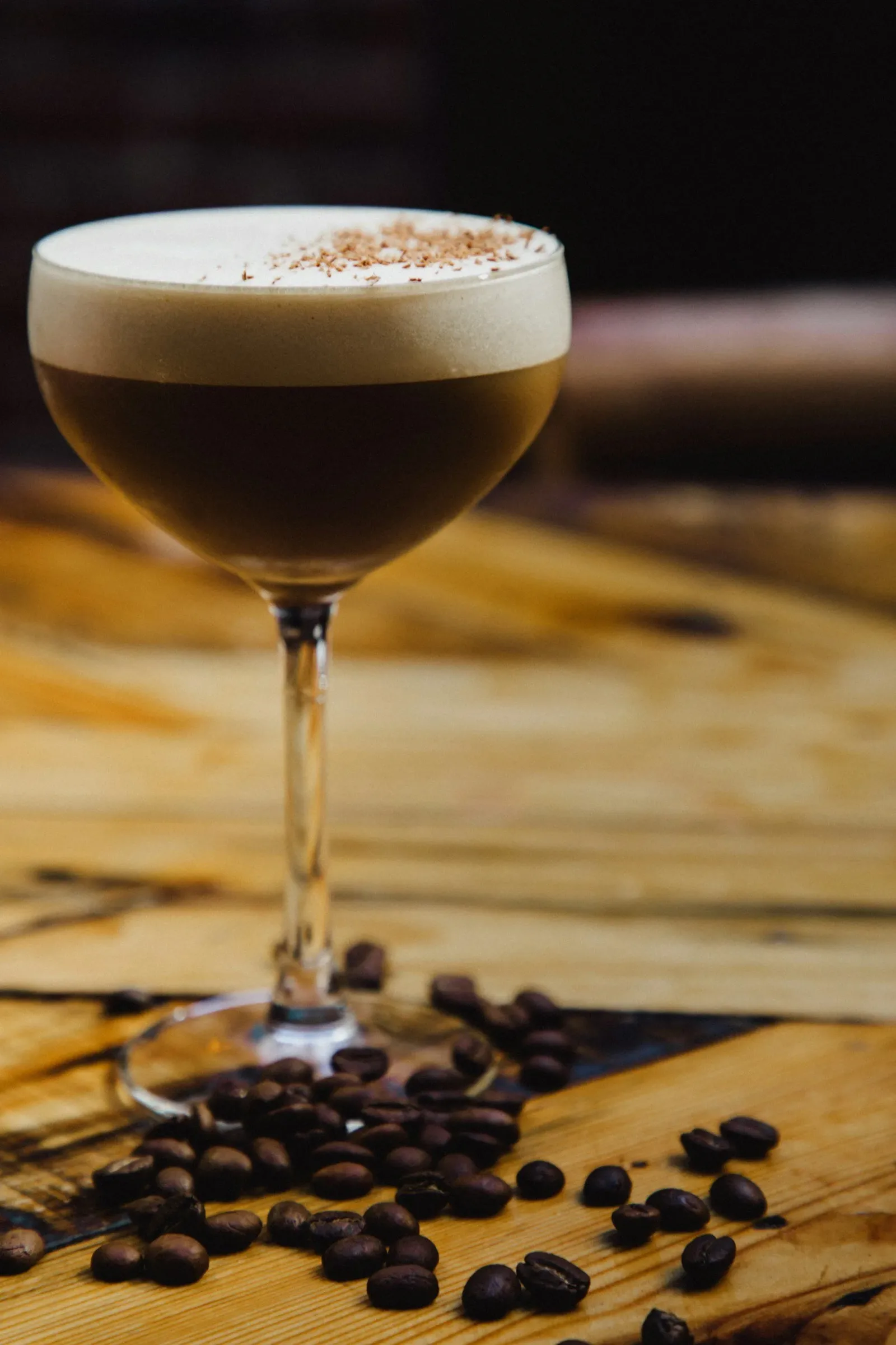 Espresso martini cocktail in a glass with coffee beans on a wooden table