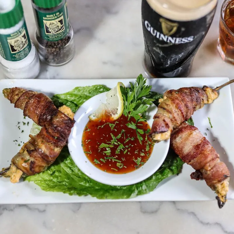 Bacon Wrapped Jalapenos, served with dipping sauce, a glass of Guinness, top view.