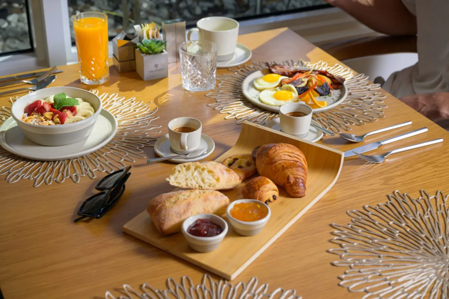 Breakfast table with croissants, fruit, coffee, and orange juice