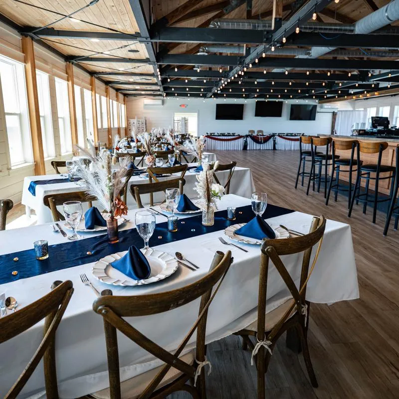 Wedding reception set up in a coastal event hall featuring decorated tables.