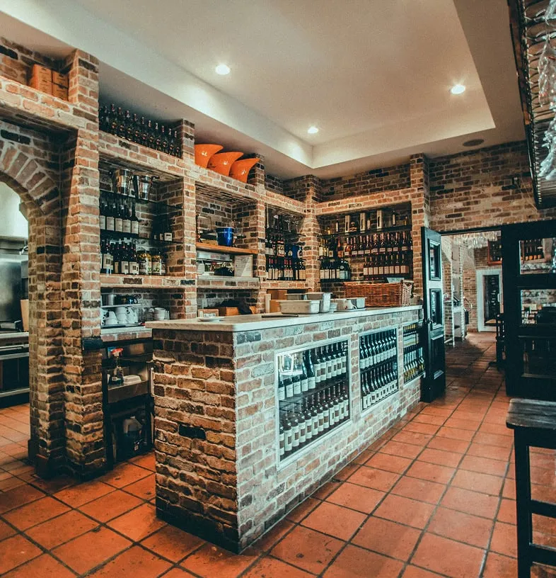 Cozy wine bar with brick walls and shelves filled with wine bottles.