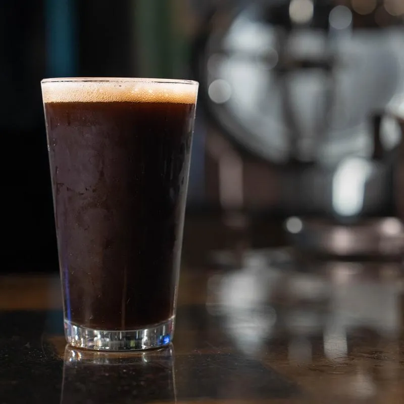 Dark beer in a tall glass on a counter.