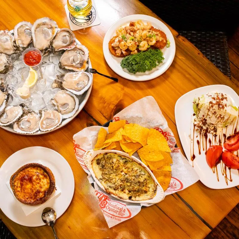 A table filled with food items: oysters spinach and artichoke dip, wedge salad.