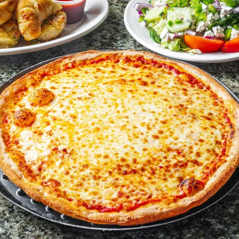 White pizza beside salad and garlic knots.