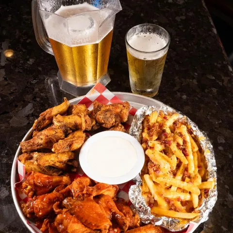 Super platter with traditional wings, boneless wings, and cheese fries, accompanied with beer.
