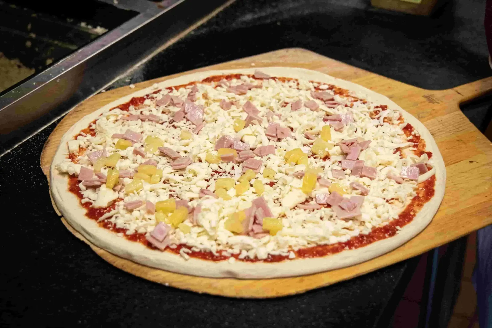 Unbaked Hawaiian pizza with ham and pineapple
