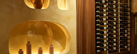 Backlit wine wall at Layali Miami with terracotta amphora and vessels in illuminated alcoves