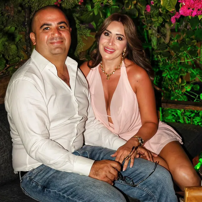 Two guests seated on the outdoor terrace at Layali Miami, surrounded by greenery and bougainvillea
