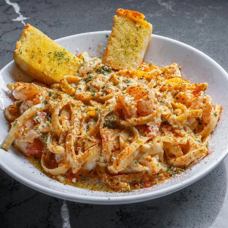 Plate of seafood pasta with two slices of garlic bread on the side.