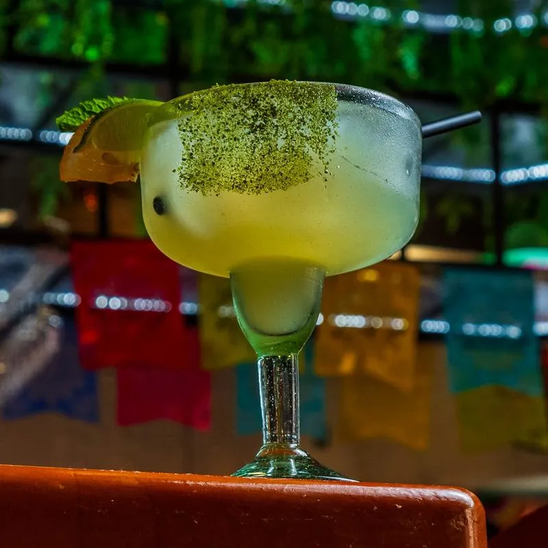 Margarita on a bar counter with Mexican festive banners.