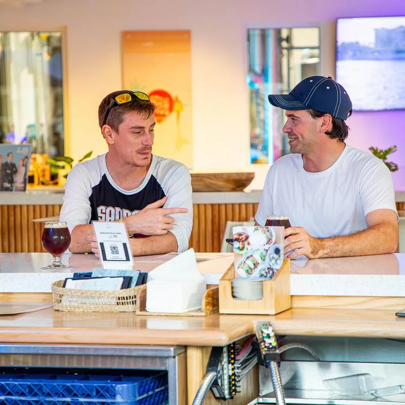Two guests having a conversation over drinks at bar counter.