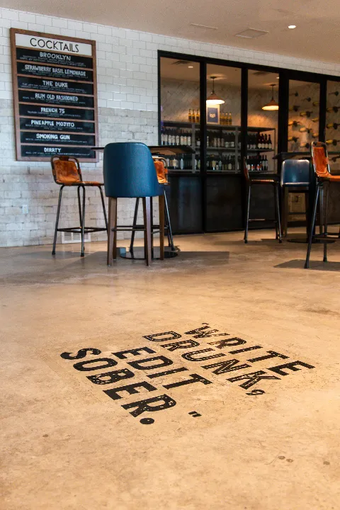 Cocktail bar with stools and sign reading “Write Drunk. Edit Sober.”