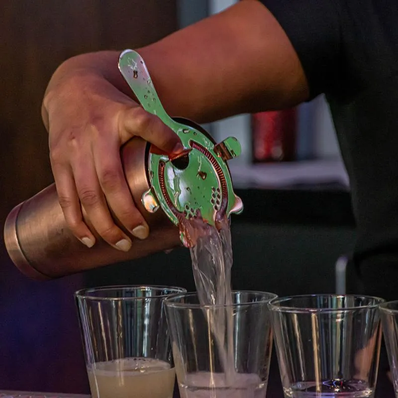 A hand, pouring cocktails.