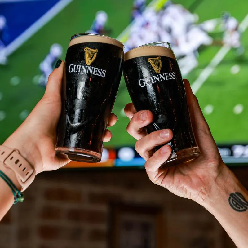 2 glasses of Guinness draft beer in a hand cheers grip