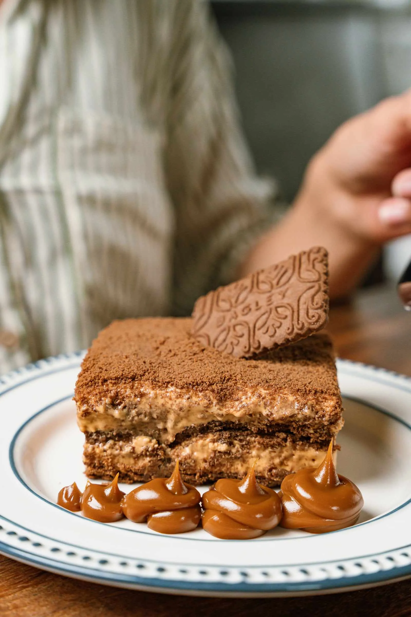 A slice of chocotorta with dulce de leche dots on a plate