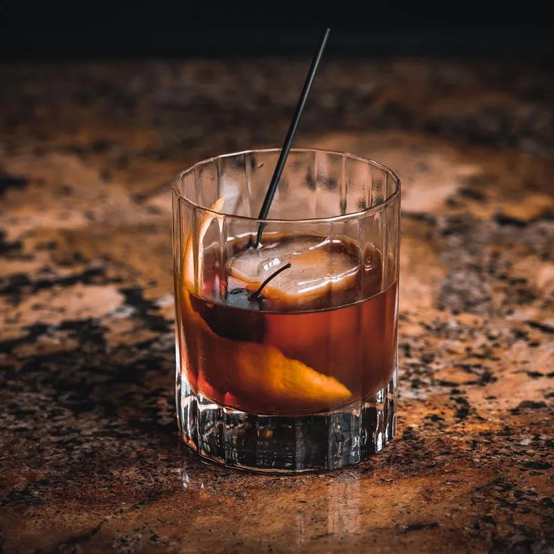 An Old Fashioned cocktail, placed on a bar top.