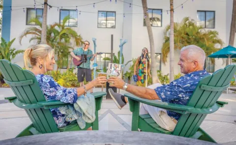 A Man And A Woman Sitting In Lawn Chairs On A Patio
