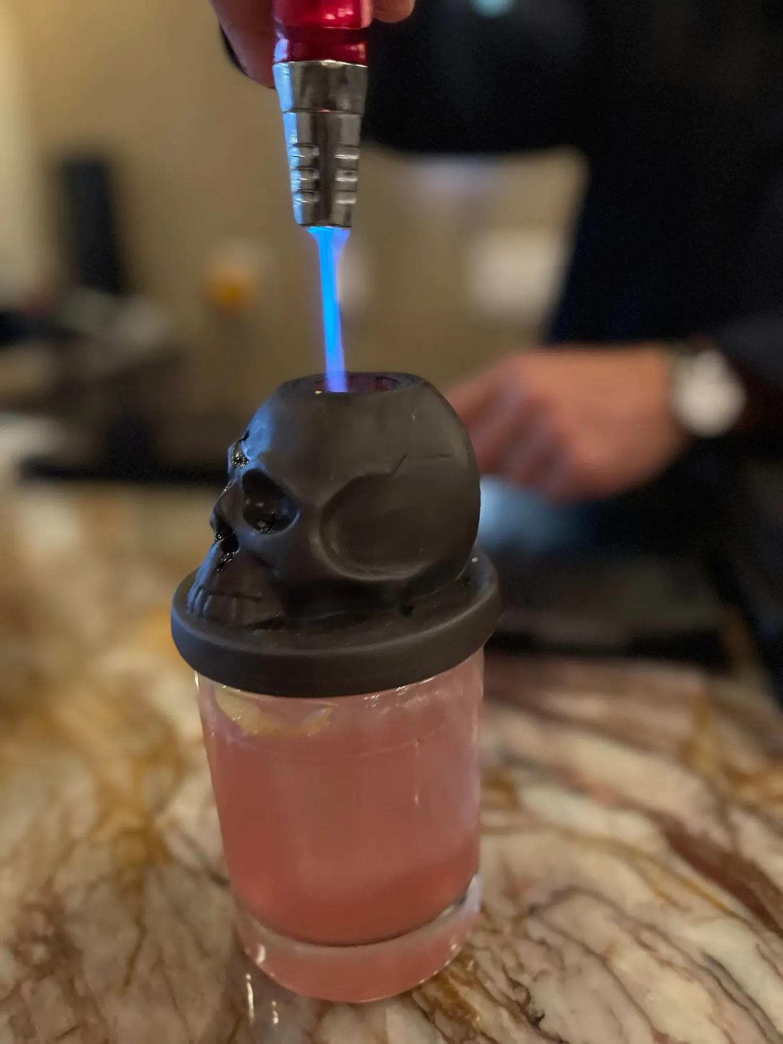 A man is sitting at a bar making a drink.