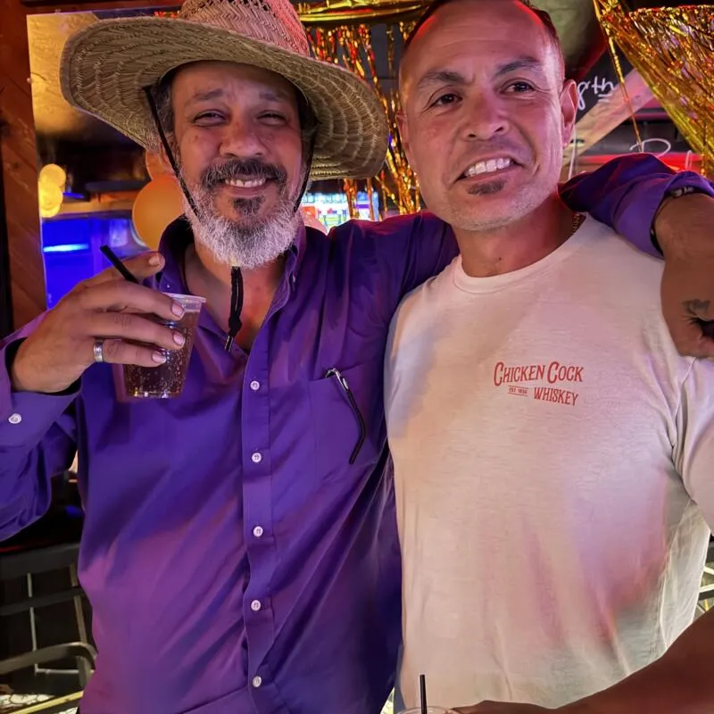 Two people smiling and holding drinks at bar.