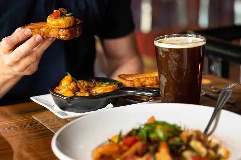 Close up of a shrimp appetizer skillet with a dark beer