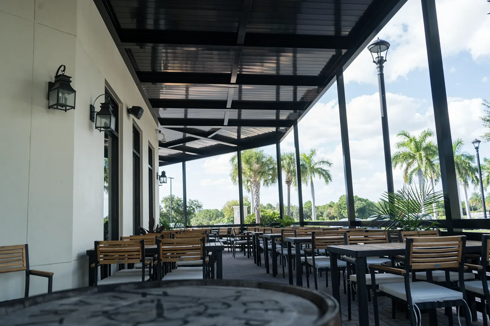 Covered patio with outdoor tables and a view of palm trees at Delany's Public House.