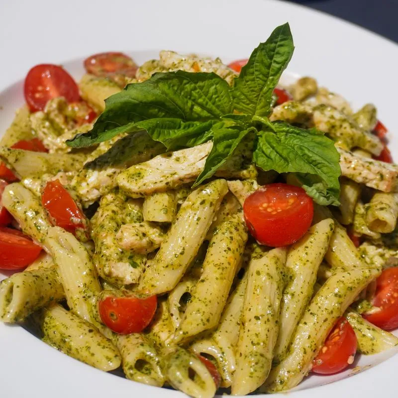 Penne pasta with chicken, pesto, tomatoes, and basil.