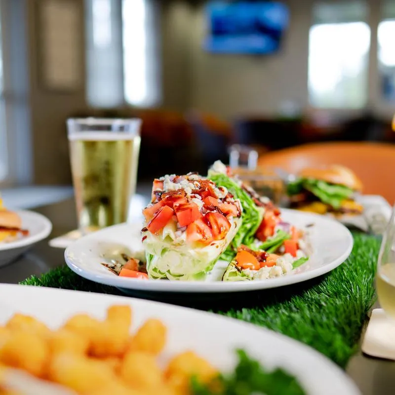Wedge salad served on the table with other dishes and a glass of beer.