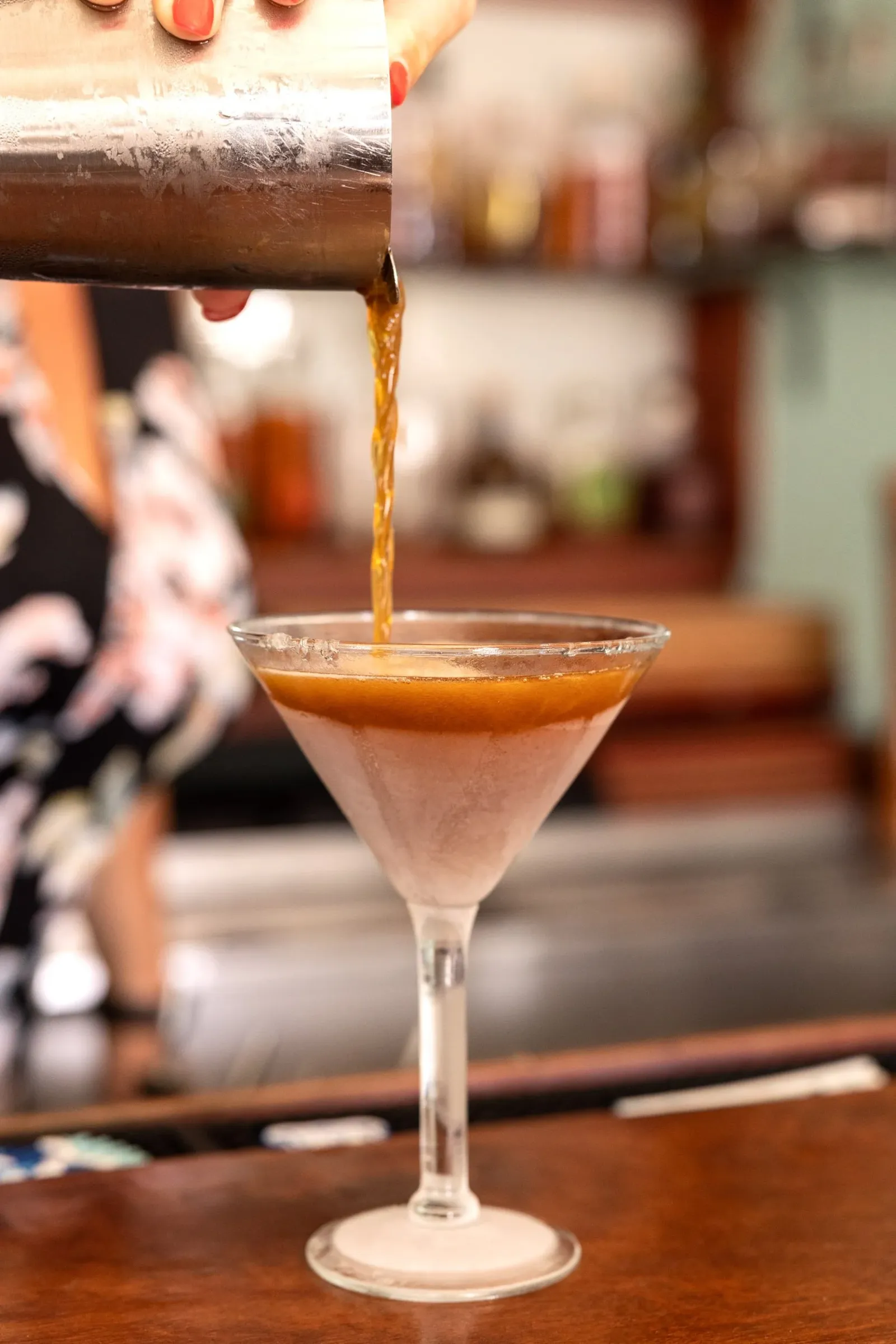 martini being poured into a glass from a shaker