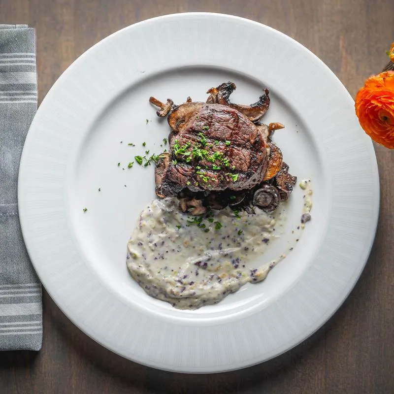 Filet mignon with cauliflower mash and roasted mushrooms on a white plate.