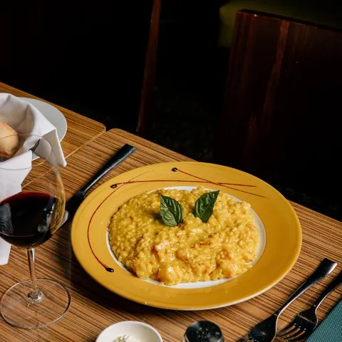 Shrimp and saffron risotto served on the table with a glass of red wine.