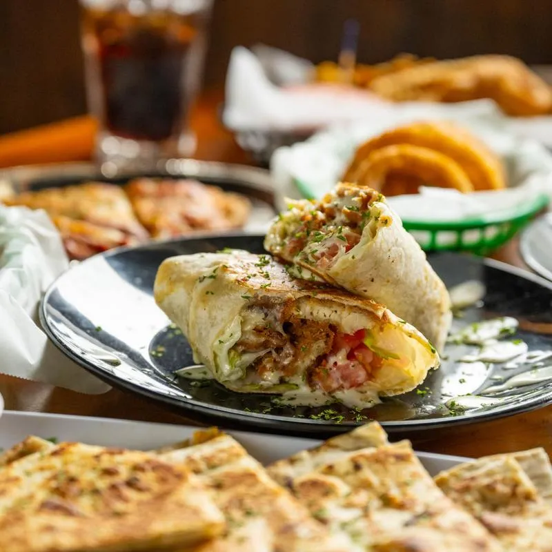 Chicken wrap surrounded by assorted dishes.