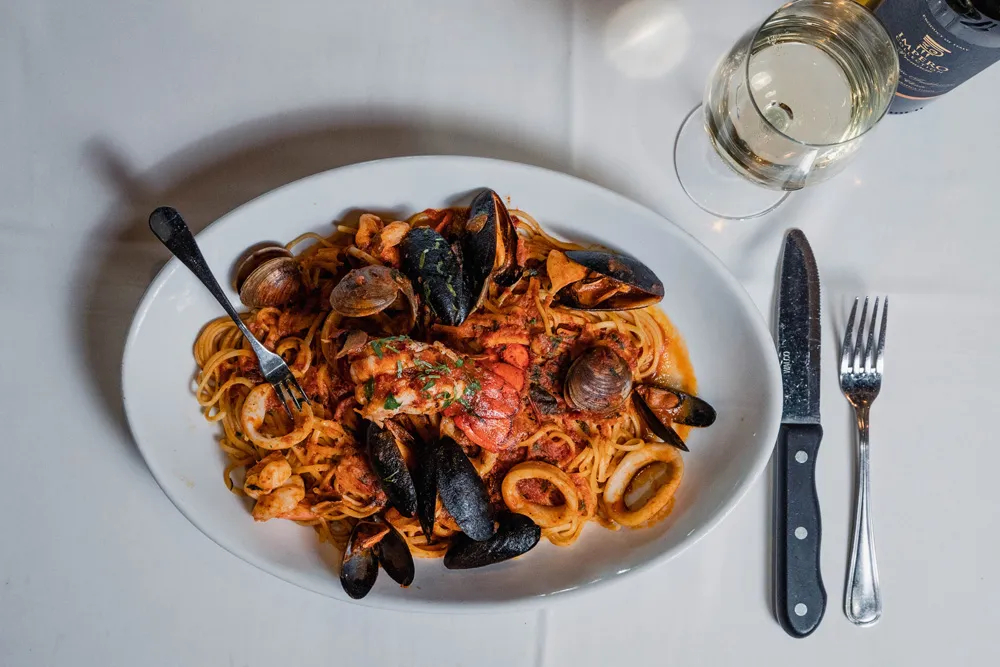 Seafood pasta with mussels in red sauce, with a glass of white wine