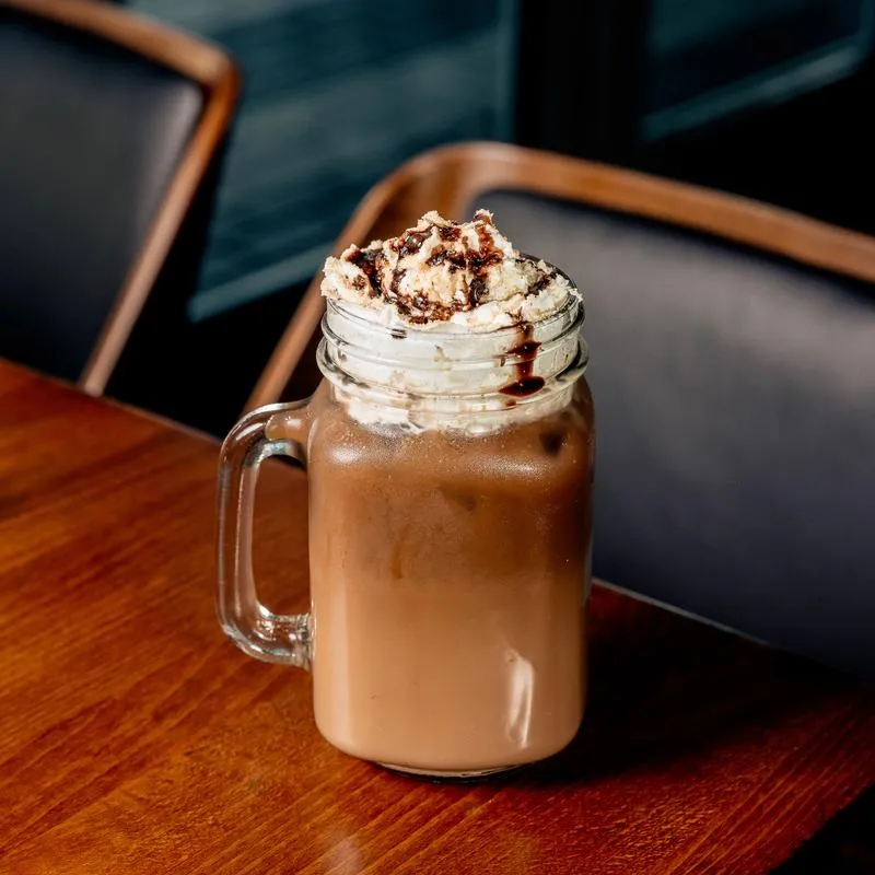 Graham Cappuccino topped with whipped cream, served on the table.