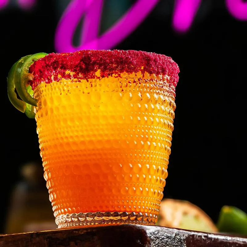 Orange drink with spiced rim and jalapeno slices.