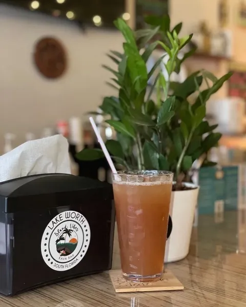 Tea in a cup on the table at island vibes kava bar next to a plant and napkin holder
