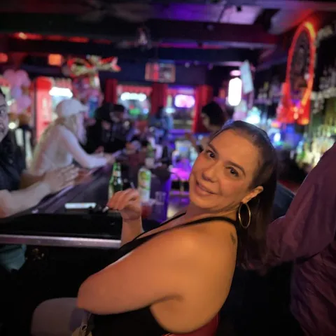 Person smiling while seated at a bar counter.
