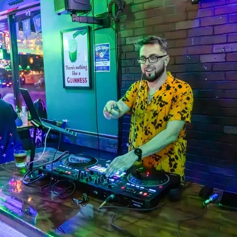 Person playing music at a DJ setup in a bar.