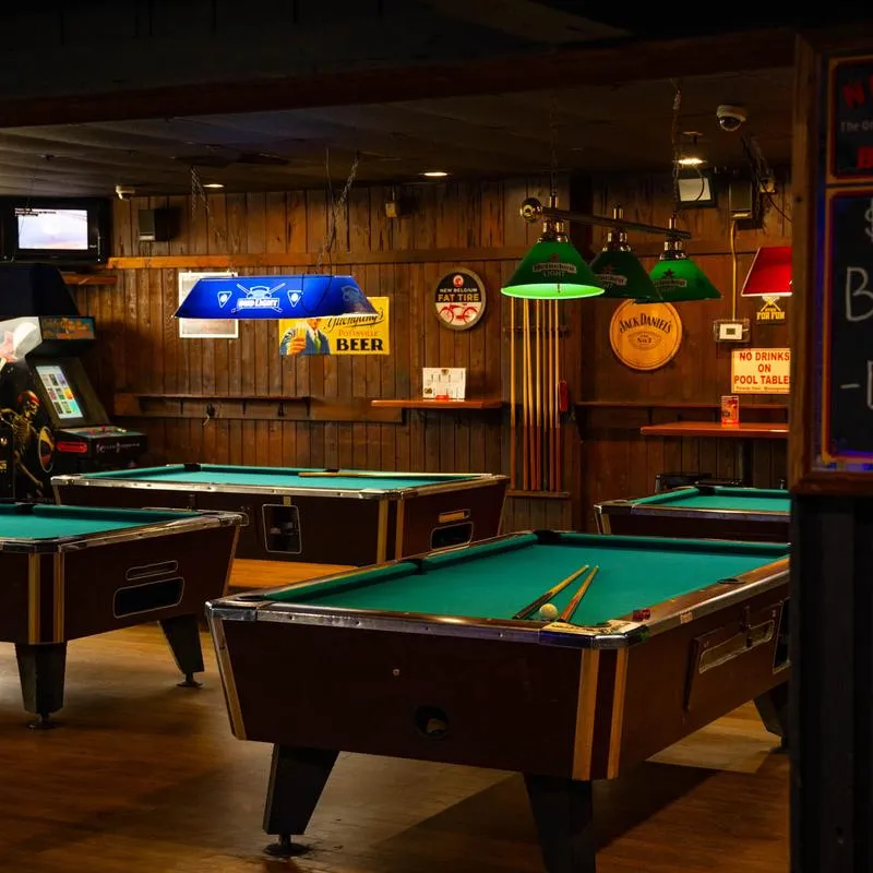 Pool tables in a room with wooden walls.