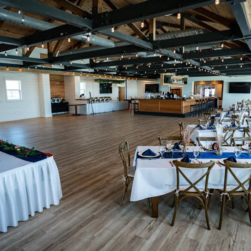 Spacious banquet hall - wooden floors, exposed beams and decorated tables set for dining.