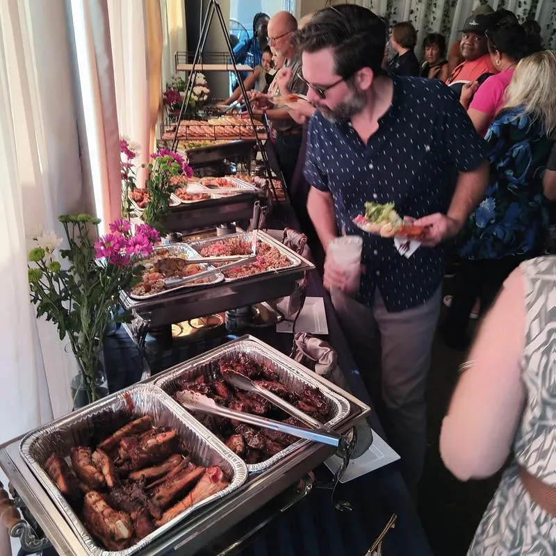 Guests picking out food from the serving containers on open table.