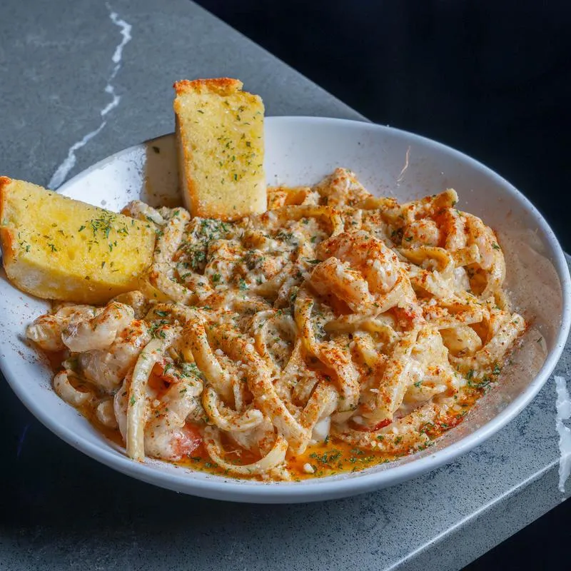 Creamy seafood pasta served with garlic bread on the side.