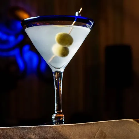 A glass of Dirty Martini decorated with olives.