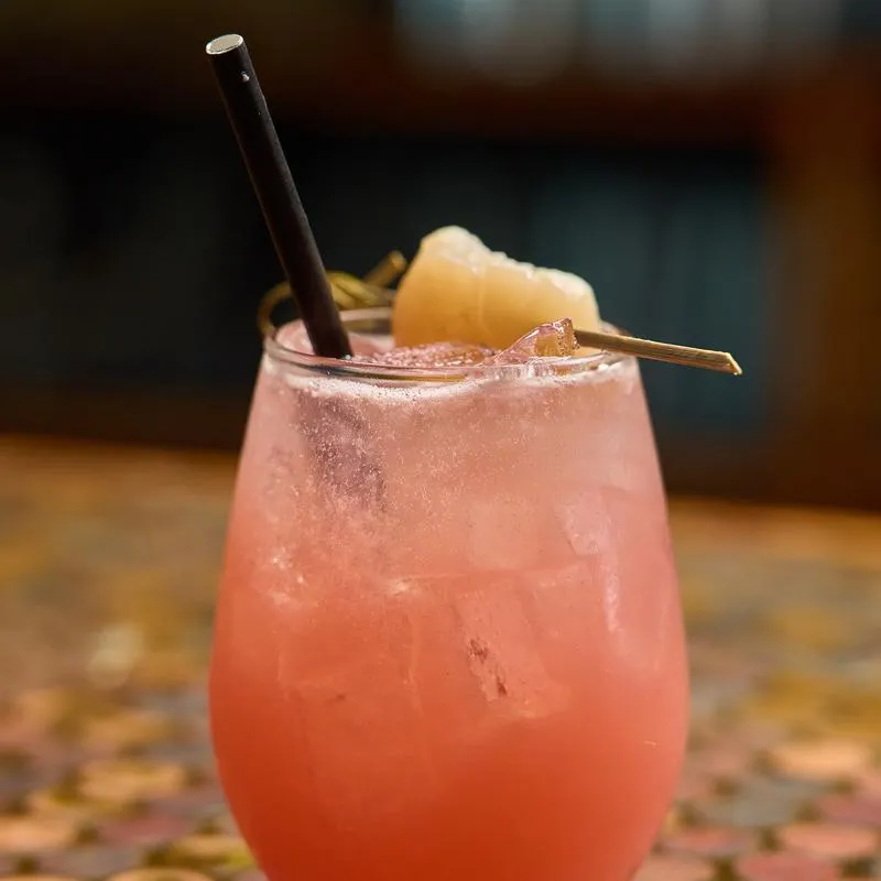 Lychee Me Alone cocktail garnished with fresh lychee fruit on a pick.