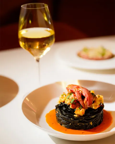 black squid ink pasta with lobster in orange sauce paired with white wine.