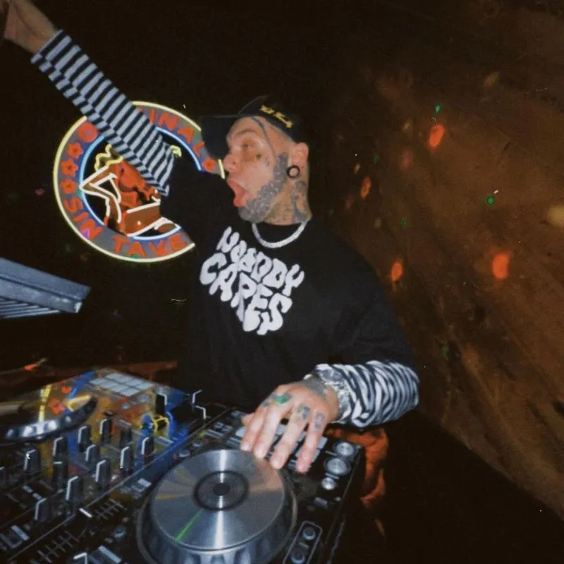 DJ mixing music on controller in dimly lit room.