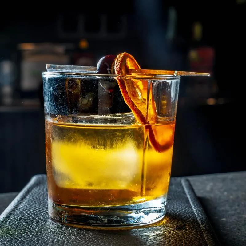 Old Fashioned cocktail with dried citrus and cherry garnish.