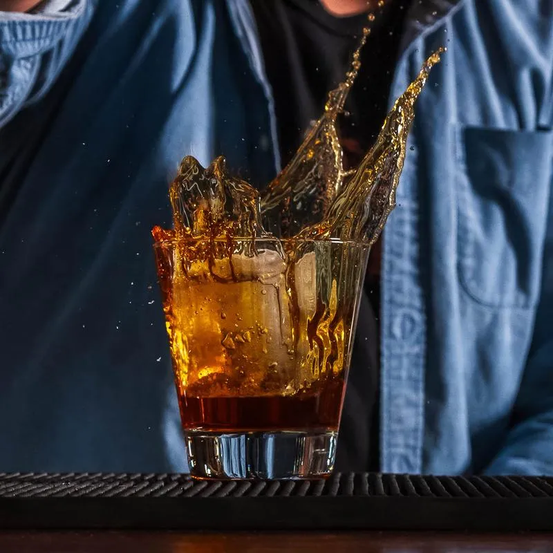 A splash of whiskey in a glass with ice cubes