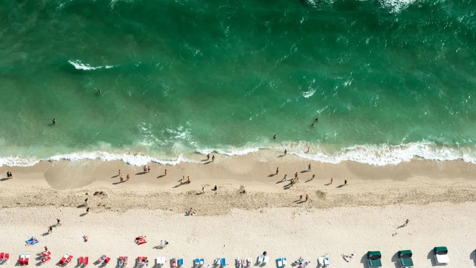 A Beach With Many People And Chairs