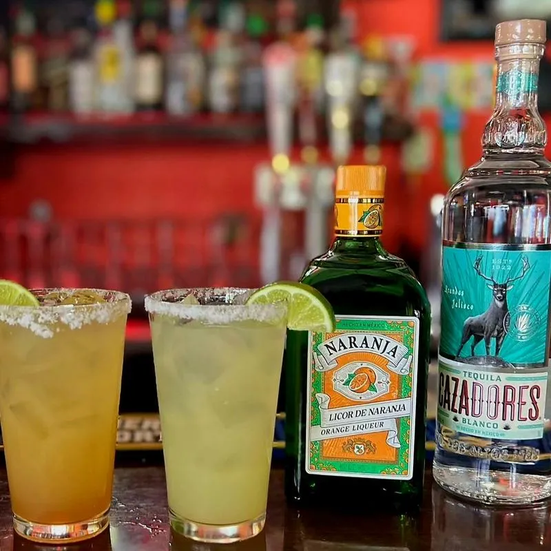 Cocktails, a bottle of Orange Liqueur, and a bottle of tequila.